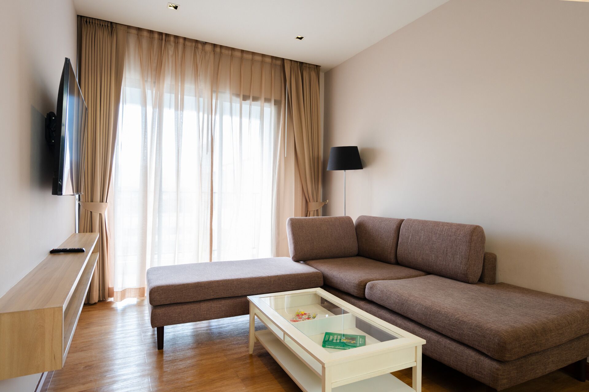 Un salon moderne avec un canapé, une table basse, un téléviseur et une lampe.
