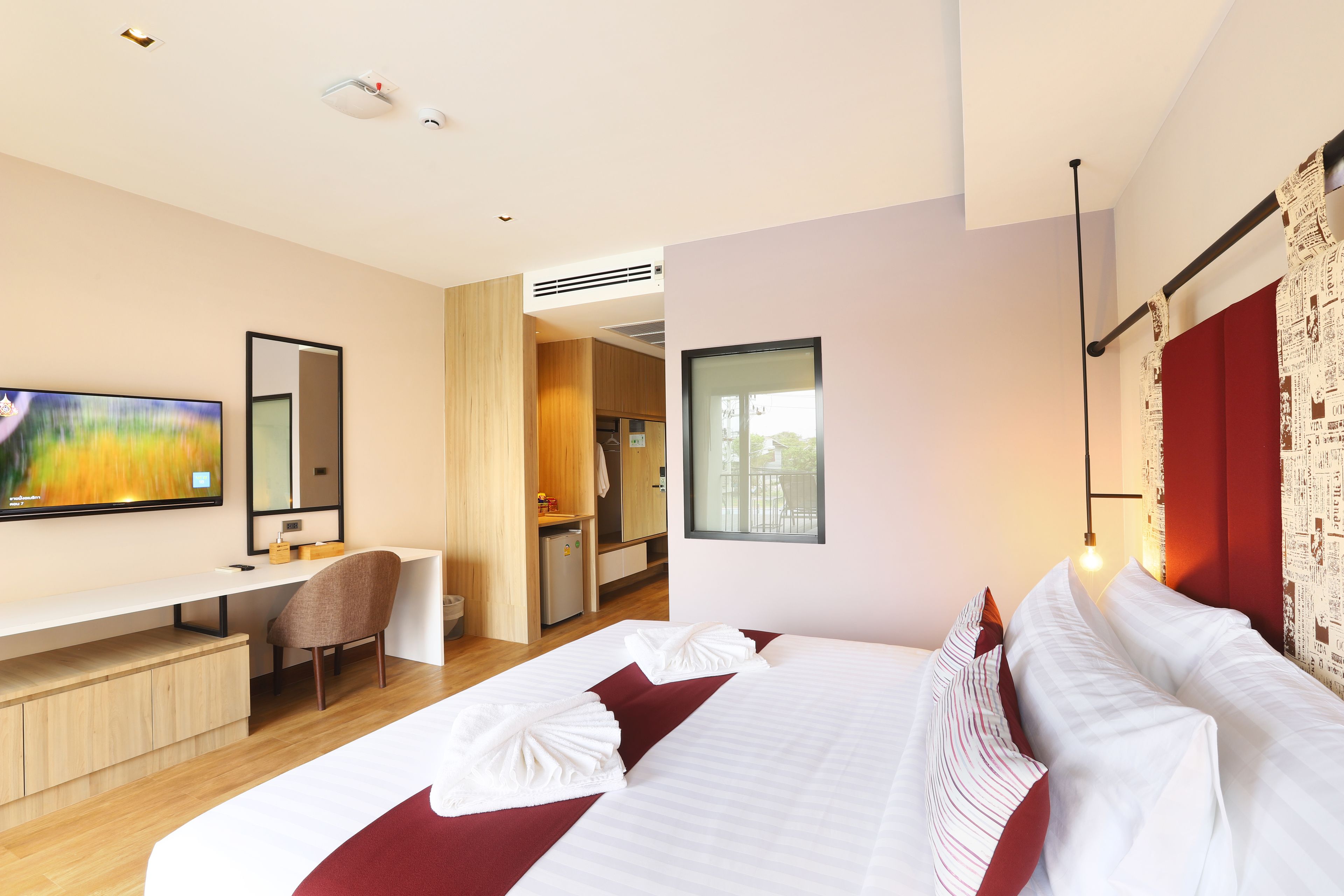 A modern hotel room with a large bed, a desk, and a television.