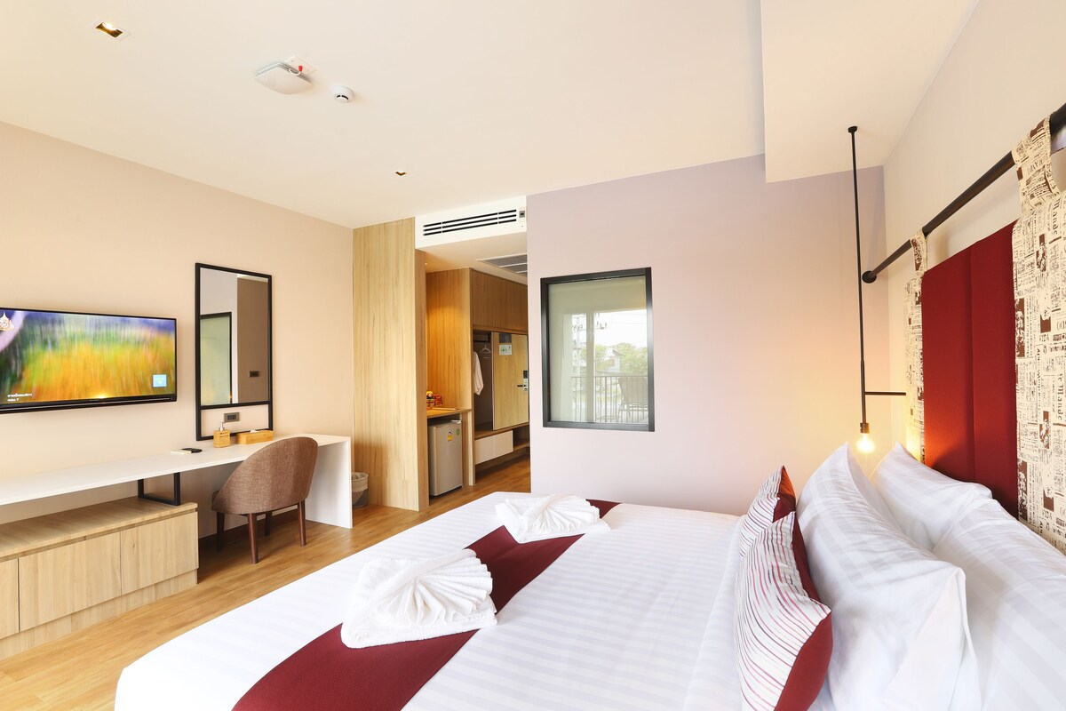 A modern hotel room with a large bed, a desk, and a television.