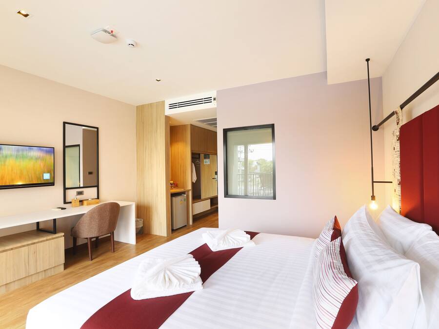 A modern hotel room with a large bed, a desk, and a television.