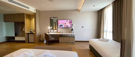 Une chambre d’hôtel avec deux lits, un bureau, une télévision et une armoire.