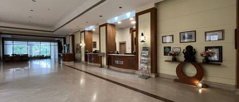 A spacious lobby with a reception desk, a cash register, and a magazine rack.
