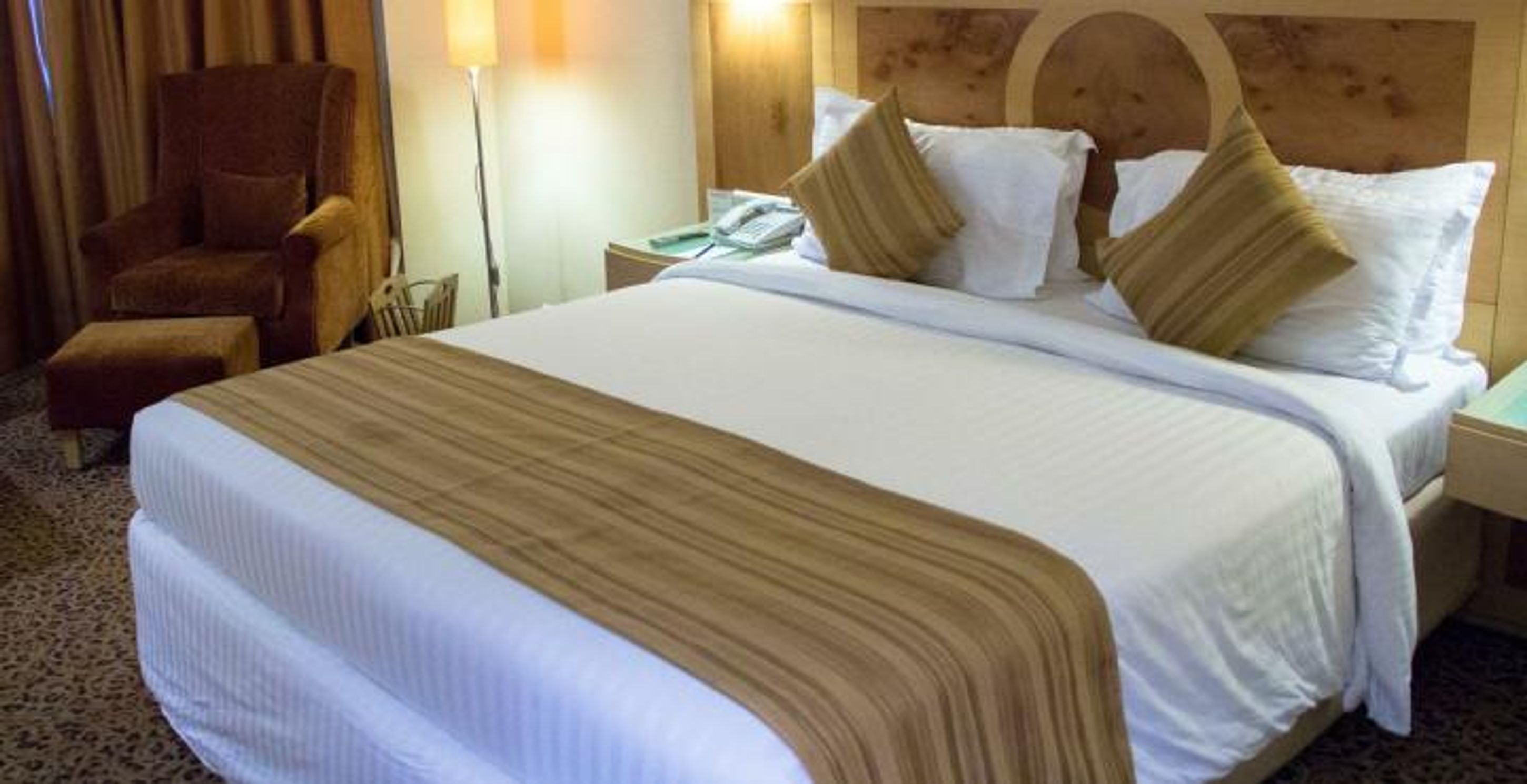 Quarto de hotel com uma cama grande, uma cadeira, uma mesa de cabeceira e um abajur.