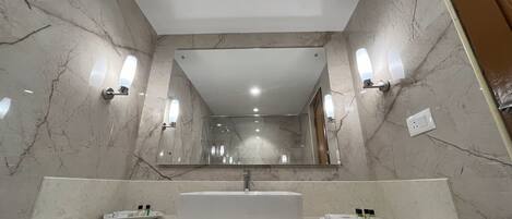 A modern bathroom with a large mirror, two sinks, and marble walls.