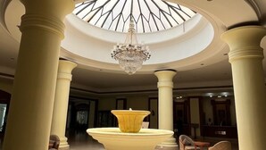 A spacious lobby with a central fountain, high ceilings, and classical columns.