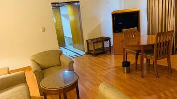 A living room with a sofa, a round coffee table, a TV, and a dining table with chairs.