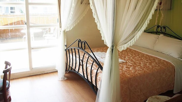A bedroom with a four-poster canopy bed, a large window with a view of the outside, and a wooden floor. - Riverbank Cottage (Wujie)