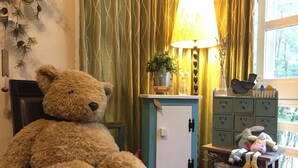 A large teddy bear sitting on a chair, a lamp, a small table with a plant, and a cabinet with storage boxes. - Riverbank Cottage (Wujie)