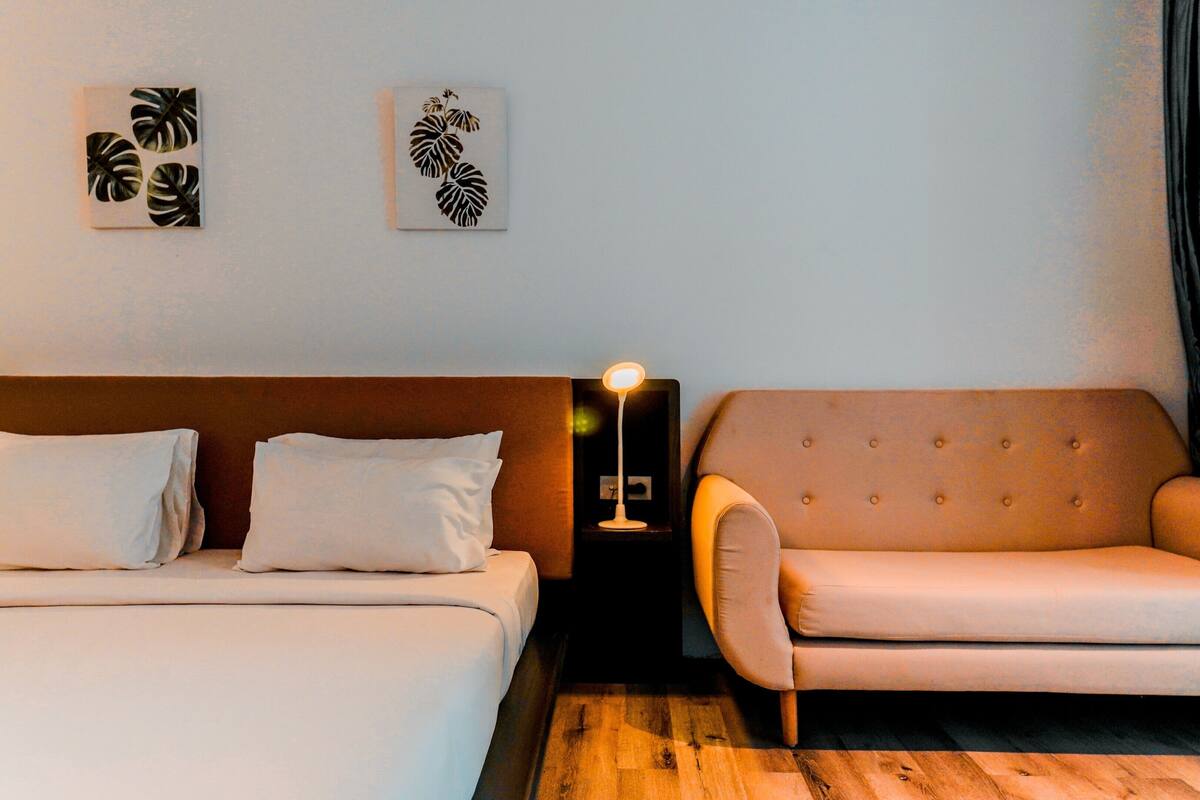 Una habitación de hotel con una cama, un sofá y dos obras de arte colgadas en la pared.