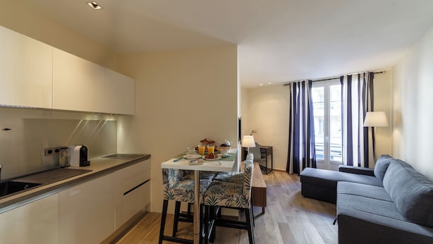 Une cuisine moderne avec un coin repas, un canapé et une vue sur la ville grâce à de grandes fenêtres.