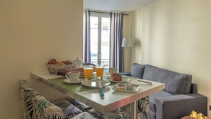 Un plateau de petit-déjeuner avec des croissants, du jus d’orange et du café, disposé sur une table offrant une vue sur la ville grâce à de grandes fenêtres.