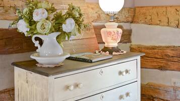 A white dresser with three drawers, a vase of flowers, and a lamp on top.