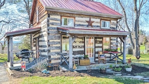 Ein rustikales Blockhaus mit einem Metalldach, einer Veranda mit Sitzgelegenheiten und einer Sternenverzierung an der Vorderseite.