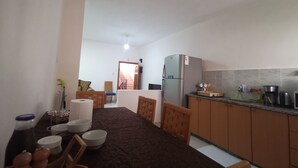A compact kitchen with a refrigerator, a coffee maker, and a microwave. There is a dining table with chairs and a small seating area with a chair and a cushion. - Visit Jerusalem & Bethlehem, Quite, Safe and free Secured parking.  (Jerusalem)