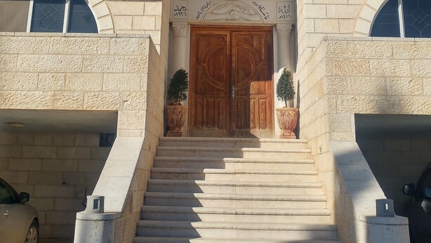 A building with a central entrance, flanked by two symmetrical wings, each with arched windows and a large wooden door. - Visit Jerusalem & Bethlehem, Quite, Safe and free Secured parking.  (Jerusalem)