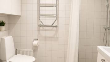 A bathroom with a toilet, a towel rack, a shower, and a radiator.