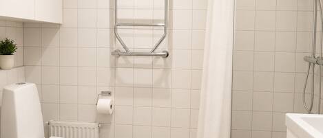 Un baño con inodoro, toallero, ducha y radiador.