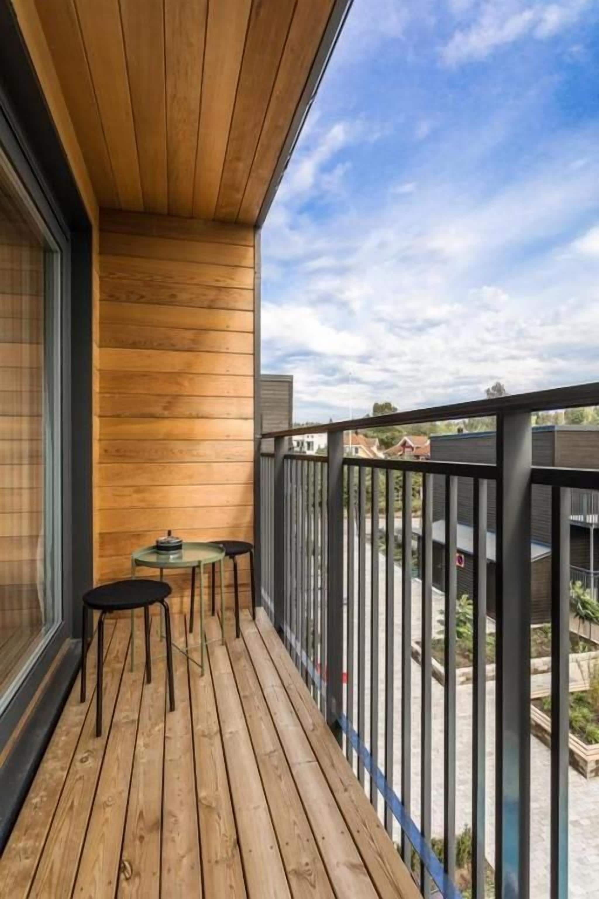 A wooden deck with a glass balustrade, a small table, and two chairs.