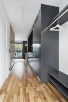 Un pasillo moderno con suelo de madera, pared oscura y una lámpara colgante.