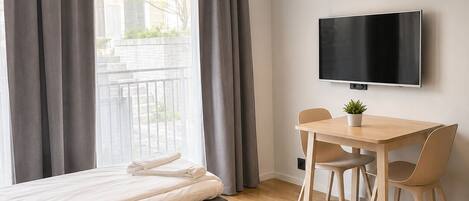 A modern bedroom with a bed, a desk, and a TV.