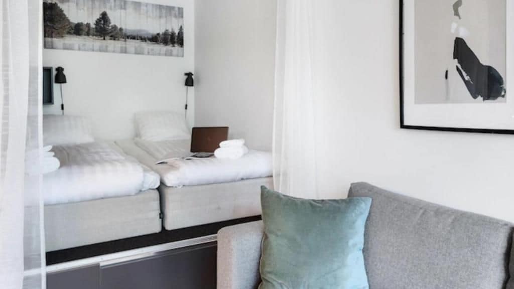 Ett hotellrum med en säng, en soffa och en inramad tavla på väggen.