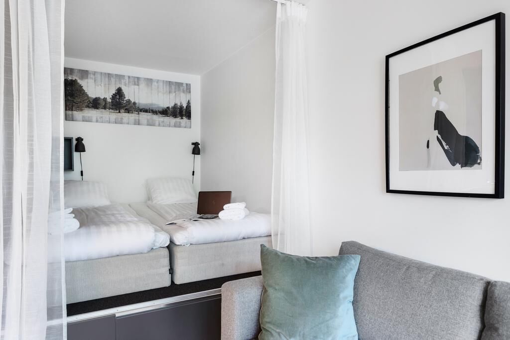 Une chambre moderne avec un lit, un bureau et une chaise. Deux tableaux encadrés sont accrochés au mur.