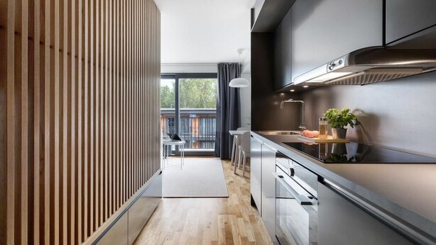 Eine moderne Küche mit einer Holzwand, Edelstahlgeräten und Blick auf einen Balkon.