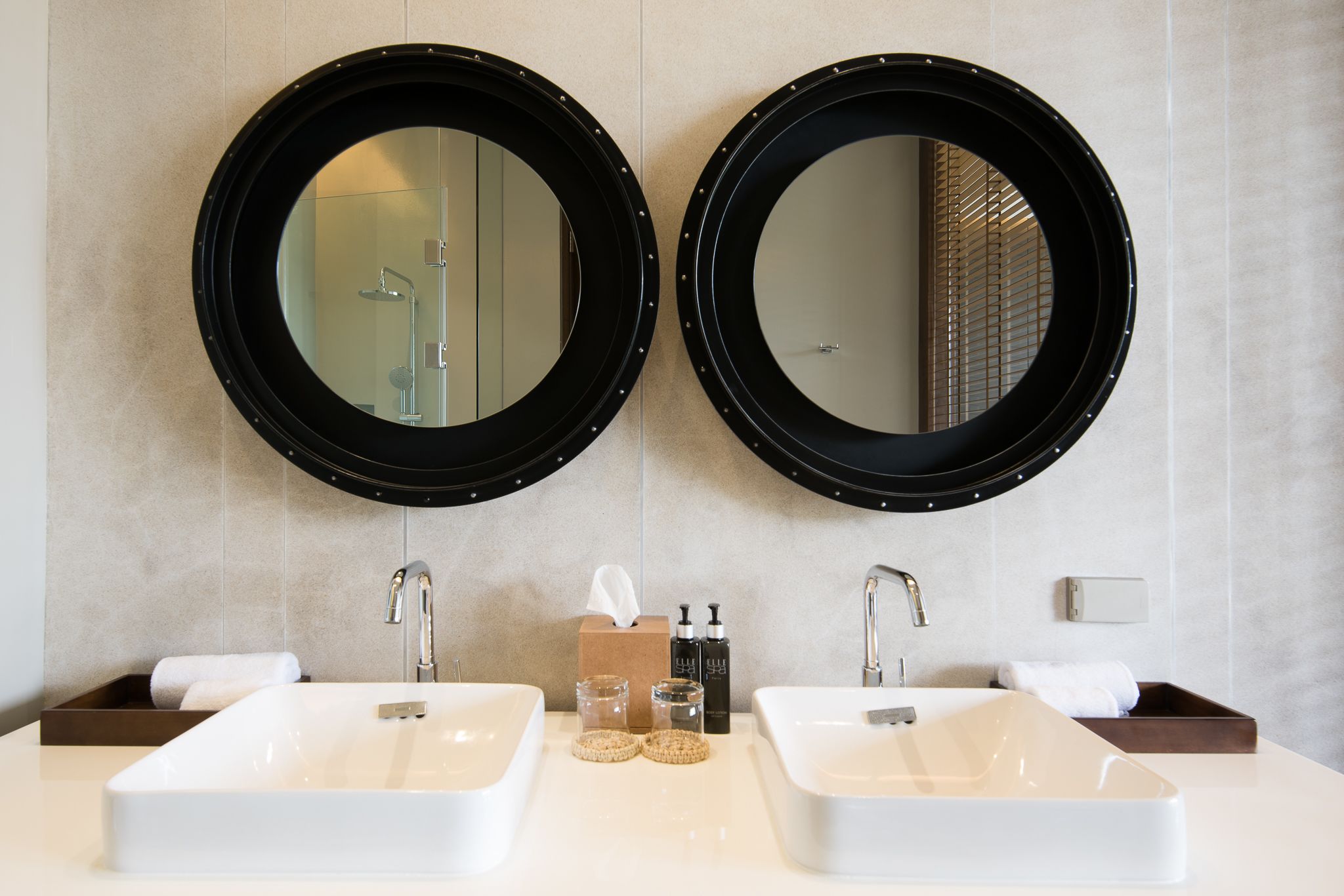 A bathroom with two sinks, two large mirrors, and a towel dispenser.