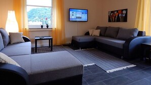 Una sala de estar moderna con un sofá gris, una mesita y un televisor montado en la pared.