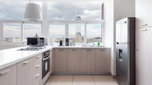 Eine moderne Küche mit großem Fenster und Blick auf eine Stadtlandschaft, inklusive einem Edelstahl-Kühlschrank.