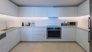 A modern kitchen with white cabinetry, a built-in oven, a microwave, a coffee maker, and a dishwasher. - Villa Hermes (Mykonos)