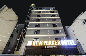 El exterior del Hotel New Yorker, con su arquitectura distintiva y señalización iluminada.