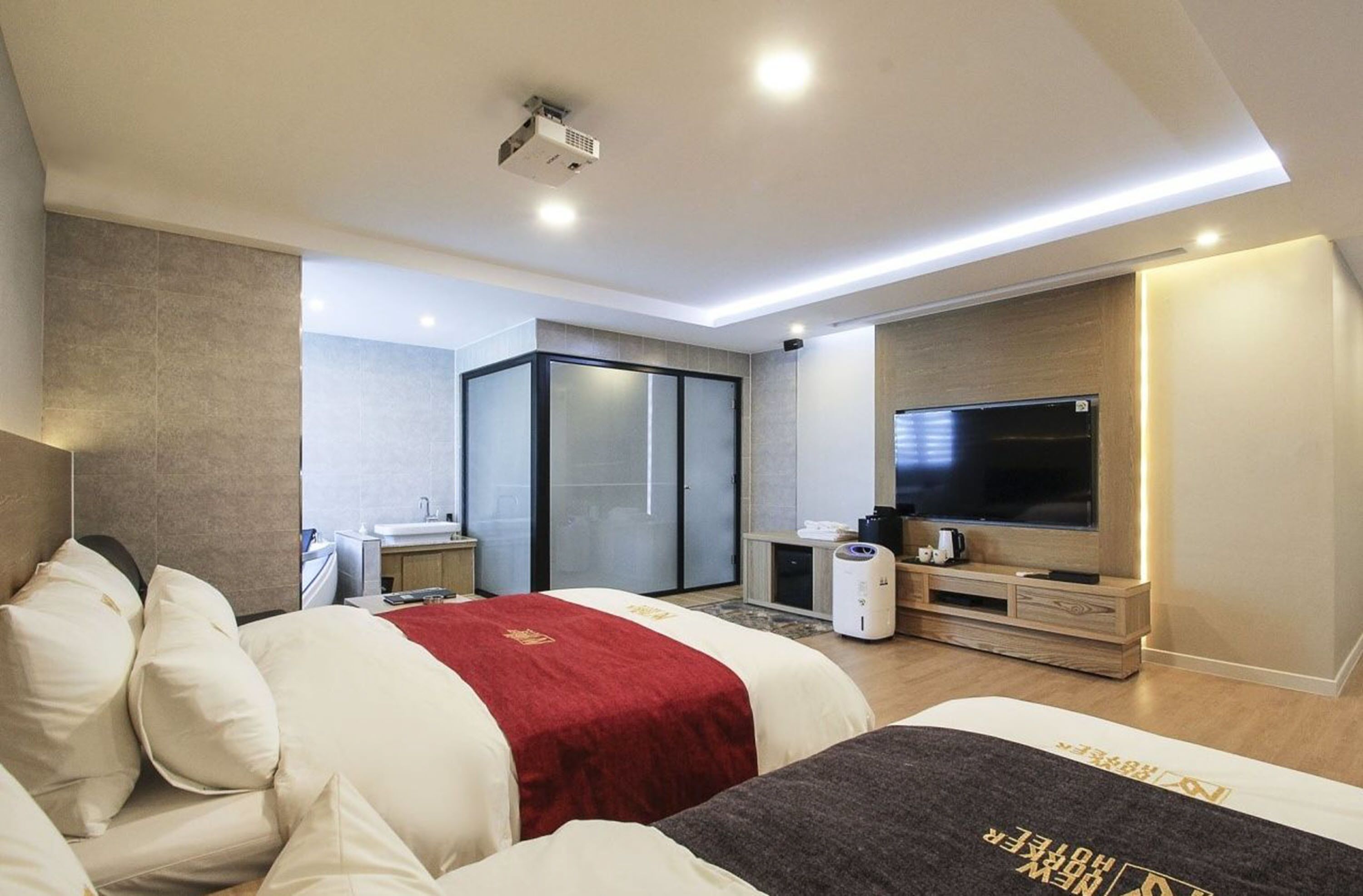 Una habitación de hotel moderna con dos camas, televisión, minibar y armario corredero.