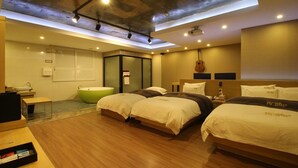 A hotel room with two beds, a green bathtub, and a wooden floor. - New Yorker Hotel (Jinju)