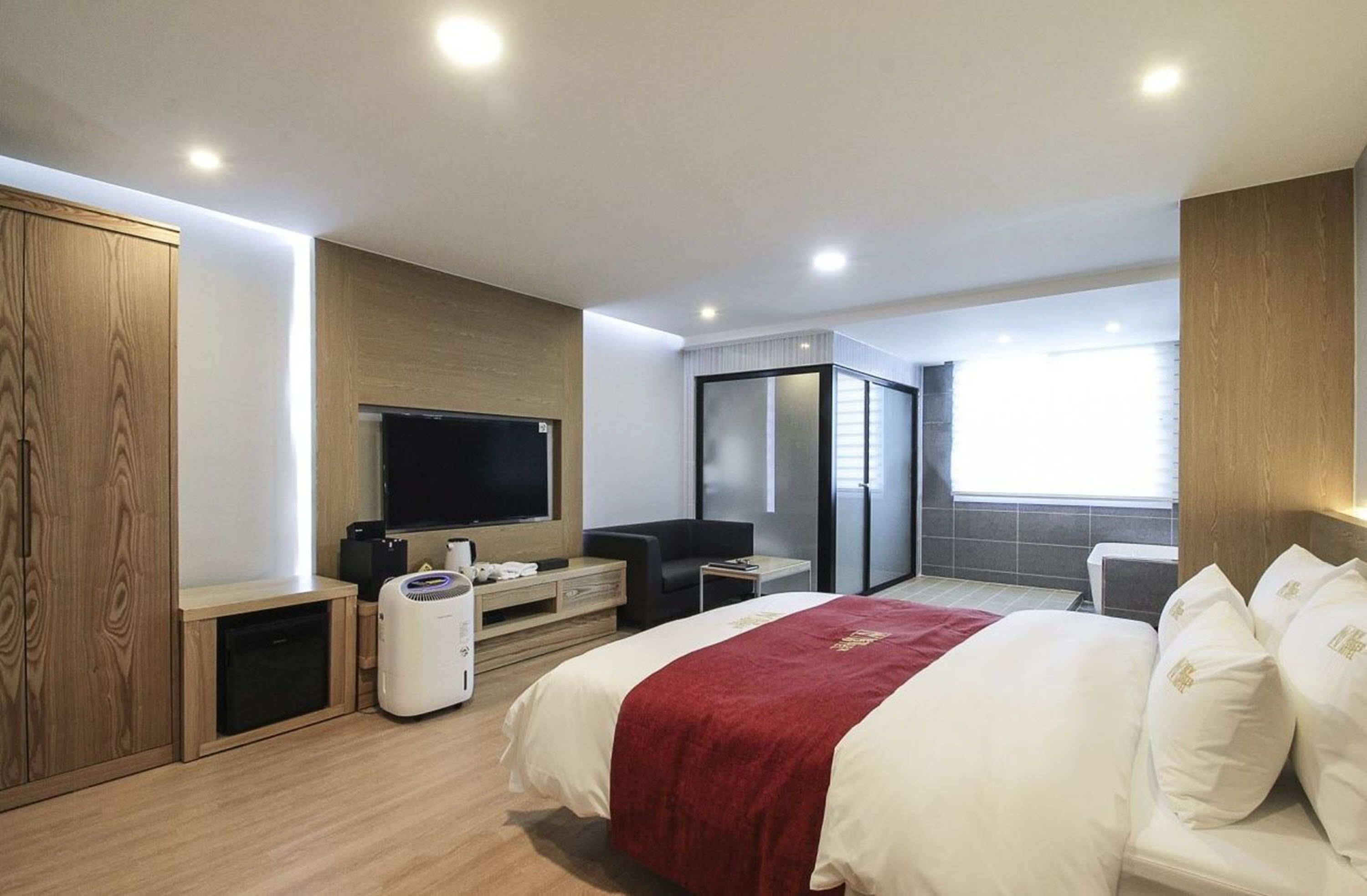 A modern hotel room with a large bed, a flat-screen TV, a desk, and a wardrobe.