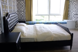 A neatly made bed with a headboard, a bedside table, and a bench with patterned cushions.