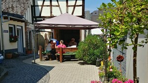 A courtyard with a wooden bench, potted plants, and a building with a sloped roof. - Apartments Rheinblick-Koblenz APARTMENT - 2 (Neuendorf)