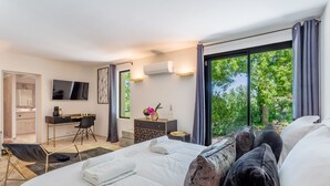 A modern hotel room with a large bed, a desk, and a view of the outdoors. - Superb 5 * rated property with spectacular view in Ménerbes (Menerbes)