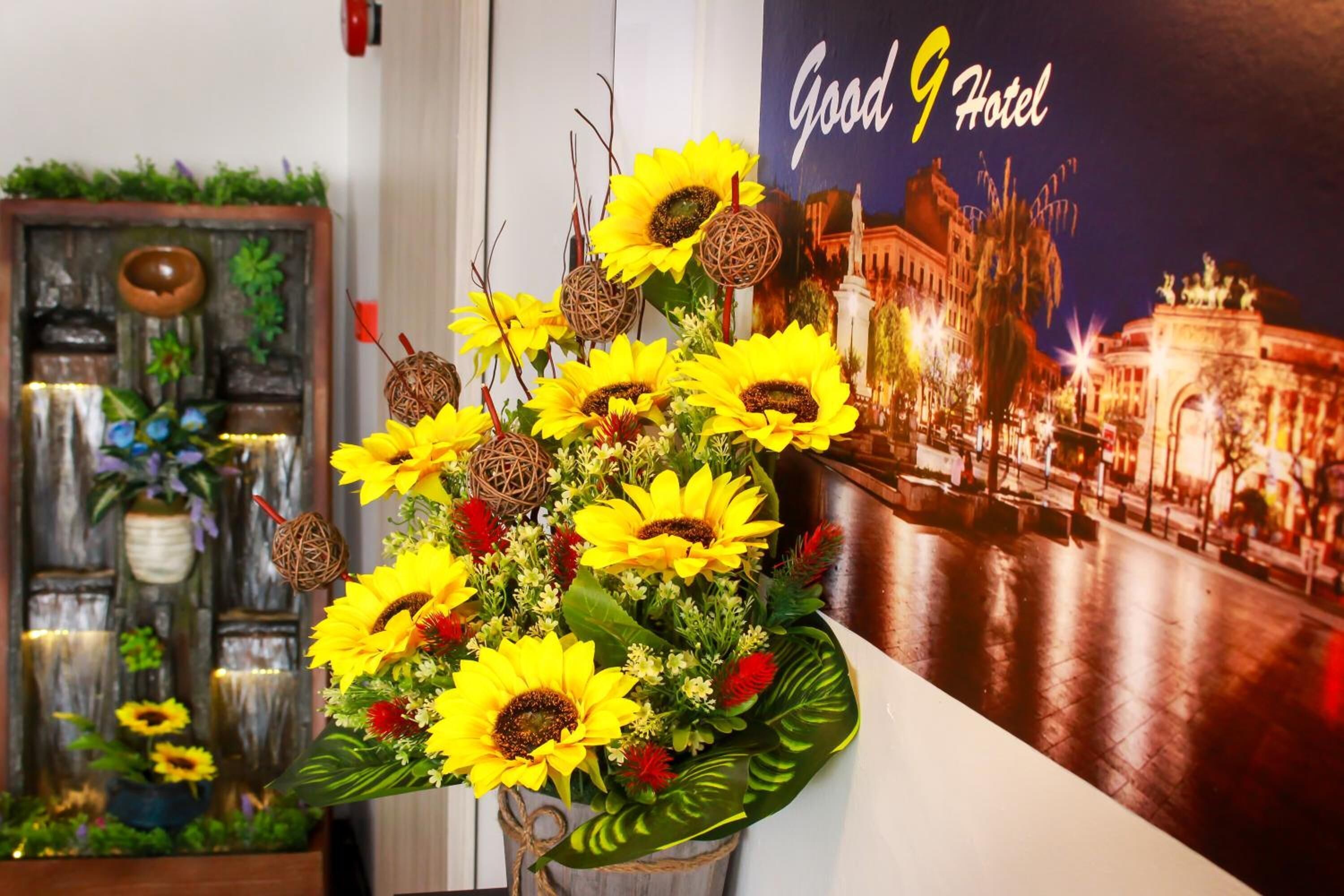 Un vestíbulo de hotel con un cartel grande de un paisaje urbano, una pieza decorativa en la pared y un arreglo floral.