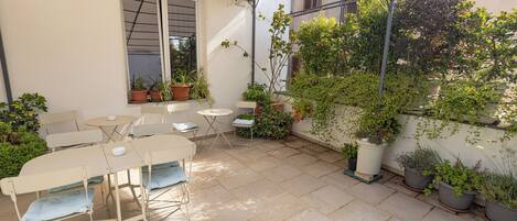A patio with a table and chairs, potted plants, and a pergola.