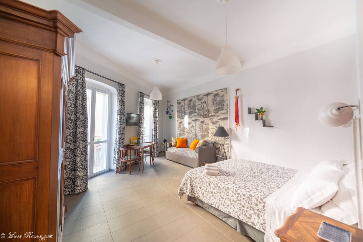 Een slaapkamer met een bed, een bureau en een bank.