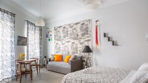 A well-lit bedroom with a bed, a sofa, a dining table, and chairs. There is a staircase leading to another level. - Janna 'e Mare (Cagliari)