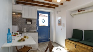 A compact kitchen with white cabinets, a blue door, and a wooden bench. - Ai Yanni Boutique Rooms - Adults Only (Rhodes)