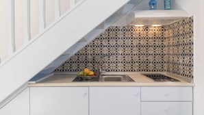 A kitchen with a white staircase, patterned backsplash, and a fruit bowl on the counter. - Ai Yanni Boutique Rooms - Adults Only (Rhodes)