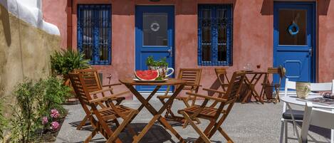 An outdoor seating area with wooden chairs and a table, a blue door, and a potted plant.