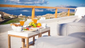 Disposição para o pequeno-almoço com mesa e cadeiras num terraço com vista para uma paisagem deslumbrante.
