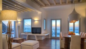 Uma sala de estar moderna com televisão, assentos e vista para o mar.