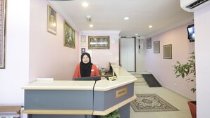 A reception desk with a sign labeled "RECEPTION" and a clock on the wall. - Super OYO 969 Hotel Pantai View (Labuan)