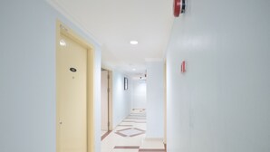 A hallway with a checkered floor pattern, a yellow door, and a red fire alarm on the wall. - Super OYO 969 Hotel Pantai View (Labuan)