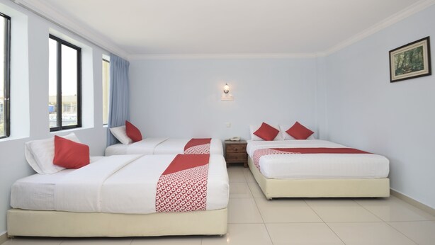 A hotel room with two beds, a nightstand, a wall-mounted light, and a window with curtains. - Super OYO 969 Hotel Pantai View (Labuan)